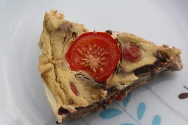 Slice of vegan quiche topped with tomato