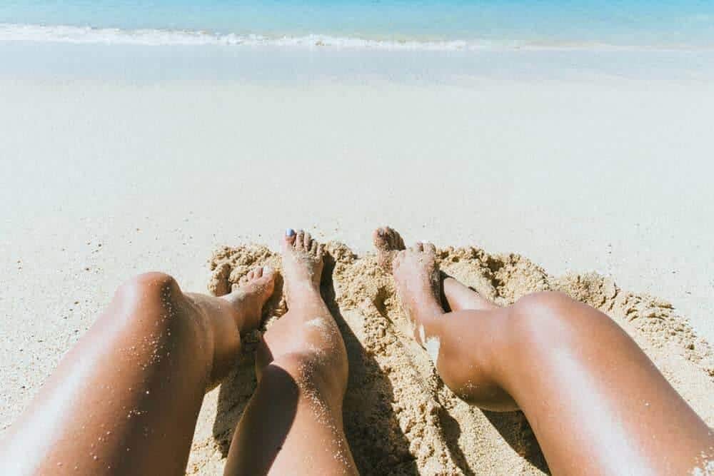 Dos juegos de patas en la arena frente al mar. guía de protectores solares veganos ecológicos