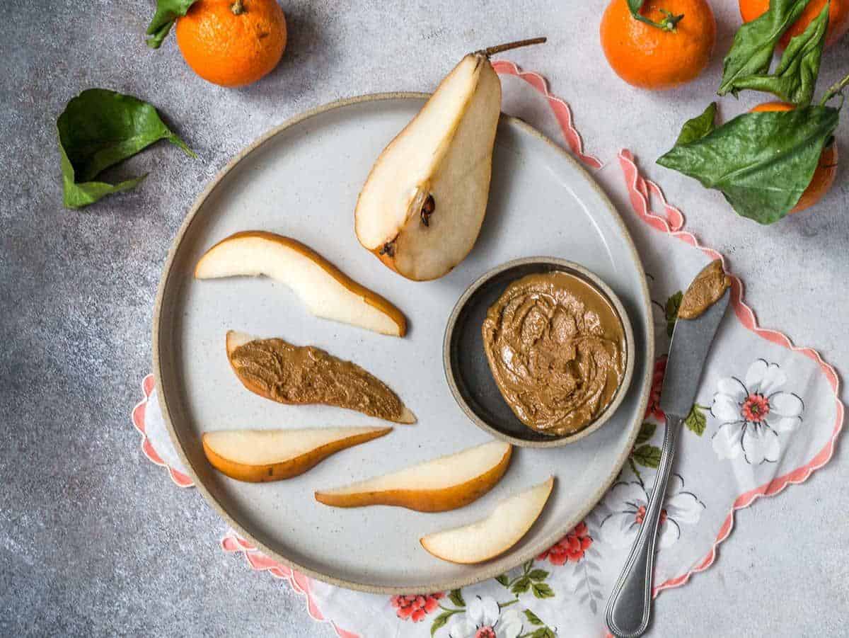 A plate containing slices of pear and nut butter