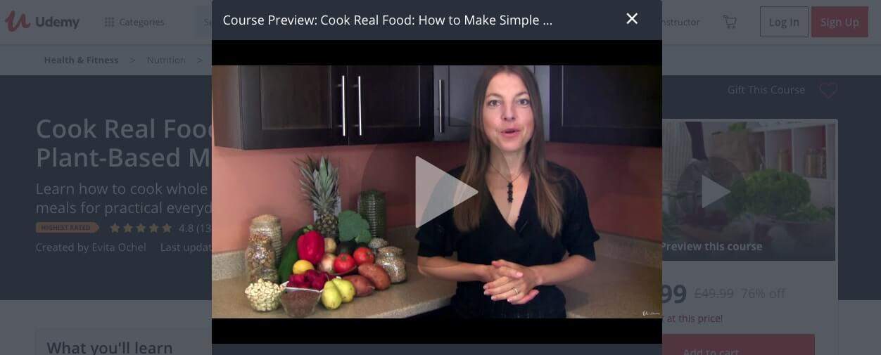 Screenshot of The simple plant-based meals cooking class on Udemy page showing instructor standing in front of stack of fruit and nuts