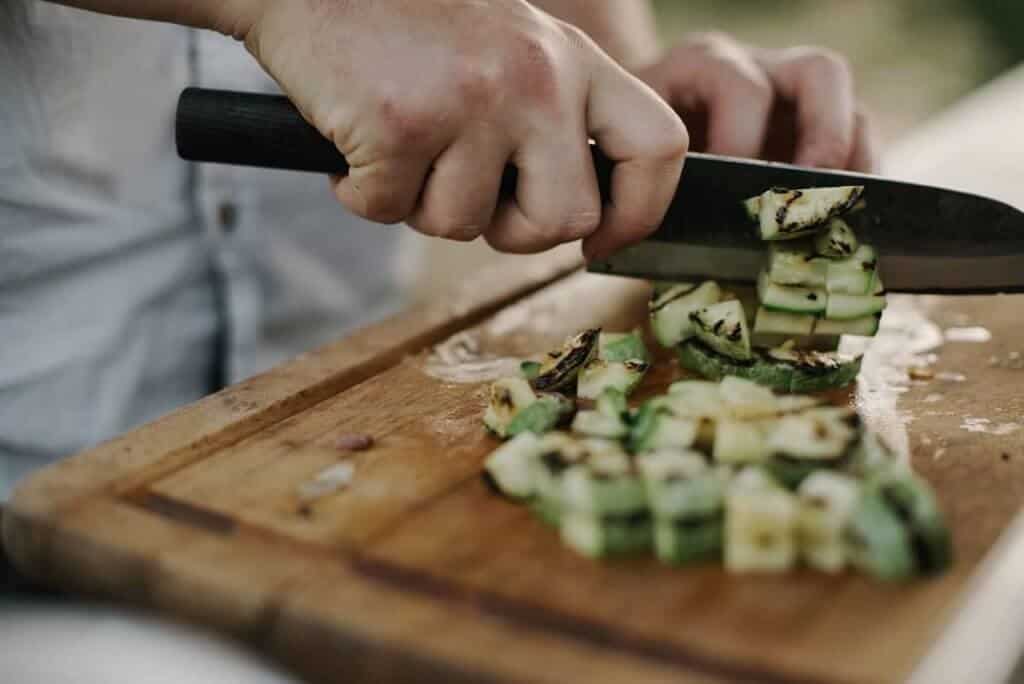 Person chopping courgette, hands shown only