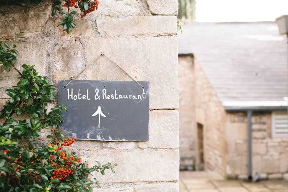 Chalkboard sign on stone wall that says 'hotel & restaurant'