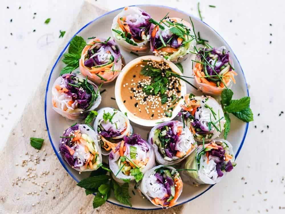 Bowl of colourful summer rolls with dipping sauce in the middle. looking for raw vegan delivery? here's where to get raw vegan plate delivery in london