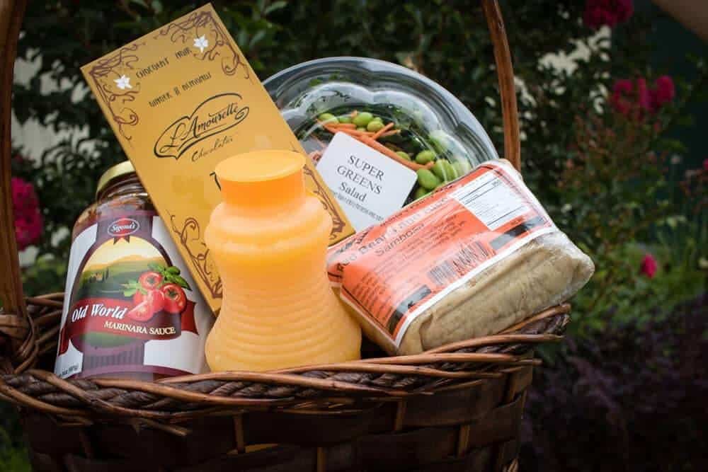 Wicker basket containing chocolate, juice, can of tomatoes and prepared foods