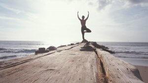 A person doing yoga on a pier with the sea in view