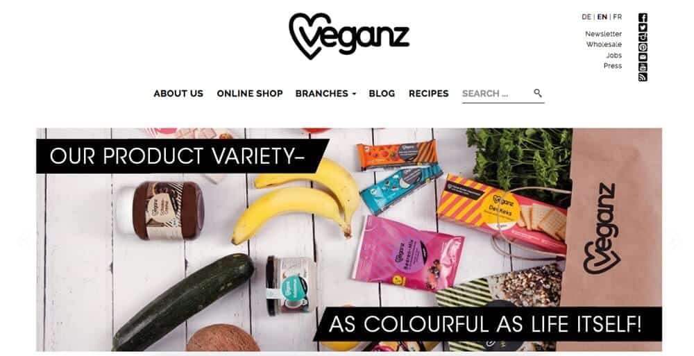 Screenshot of Veganz site showing a shopping bag with snacks, fruit and veg to one side