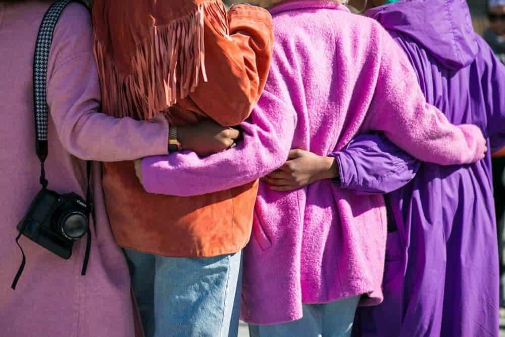 View from behind of four people with their arms around each other