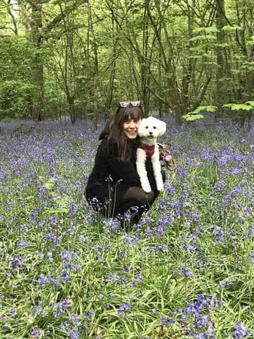 The author, Caitlin Galer-Unti, pictured with her dog, Benito, amongst the bluebells in the woods outside London