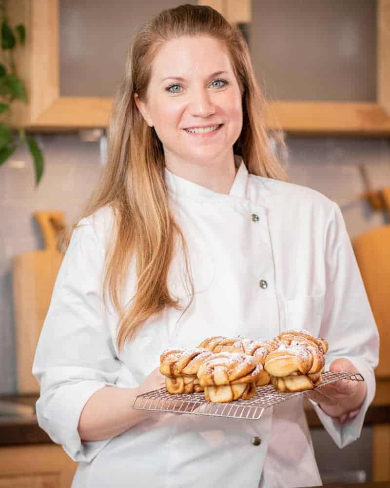 A pastry chef holds a plate of baked goods