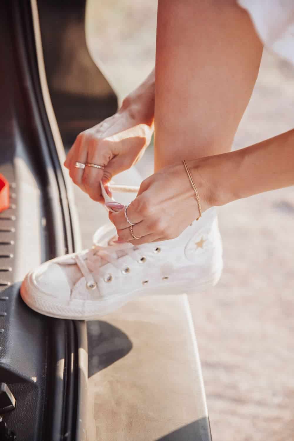 Person shown lacing up white high top sneakers