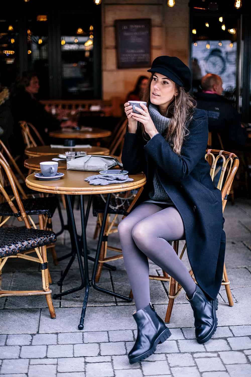 Woman drinking coffee at a cafe table wearing Bhava Chelsea boots