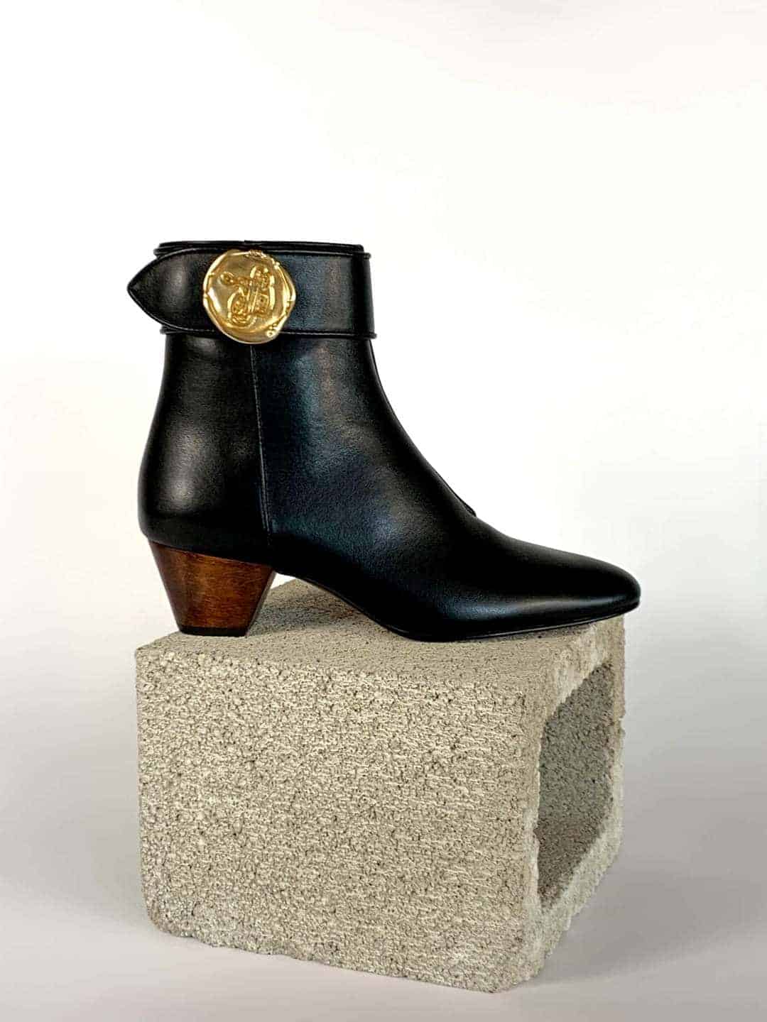 Black ankle boots with wooden block heel and decorative gold medallion