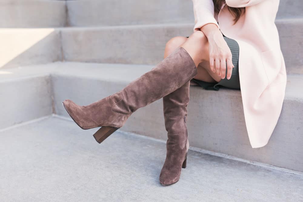 Woman wearing knee high heeled brown boots sitting on steps