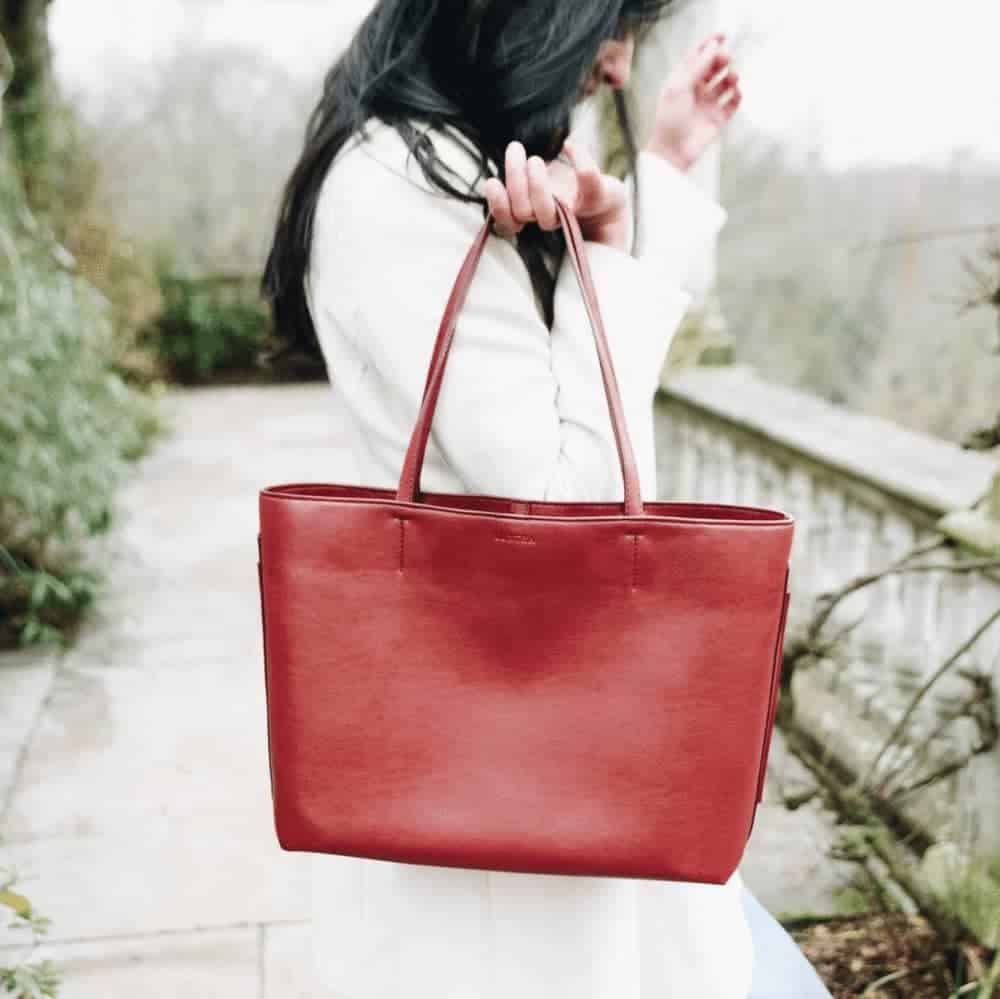 Person holding burgundy tote bag