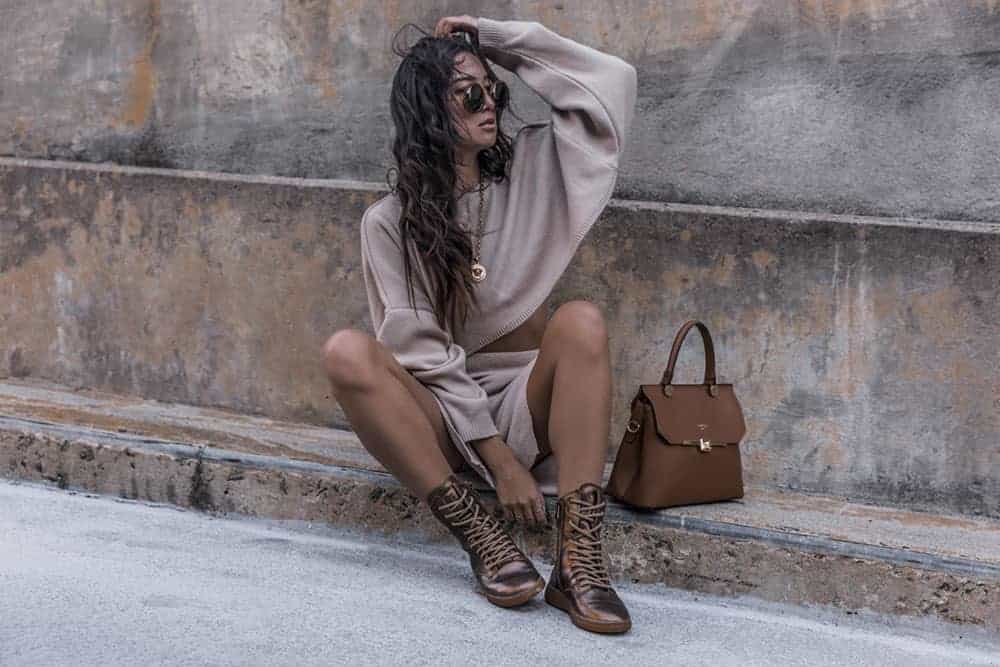Woman sitting on stone steps with a brown satchel bag next to her