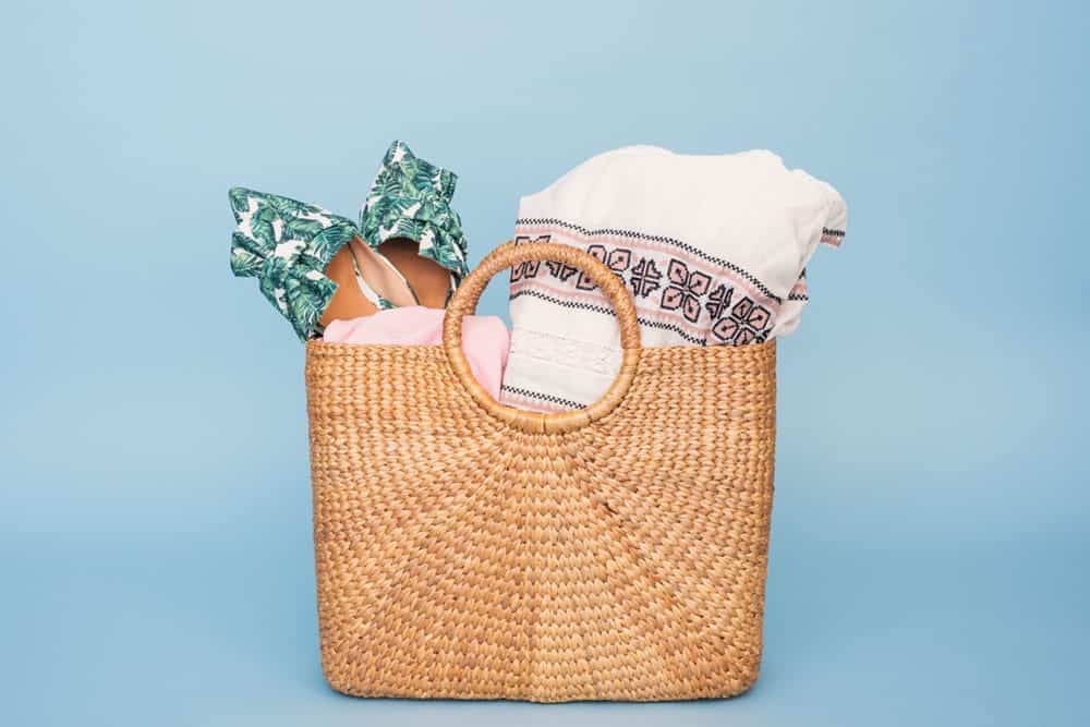 Straw tote bag holding a beach towel and pair of showing