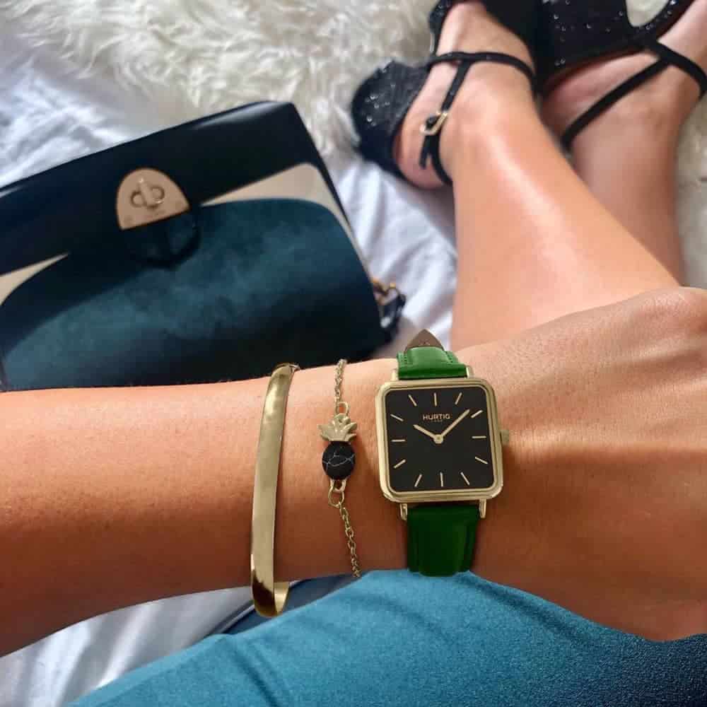 Watch with square black dial, green strap and gold hardware