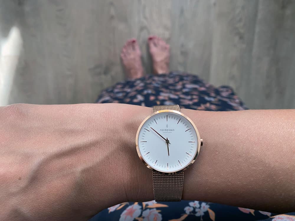 Picture of author's wrist, showing watch with white dial, rose gold hardware and rose gold mesh strap