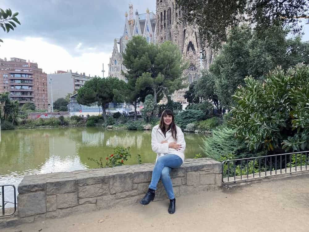 Author is pictured wearing white vegan faux shearling jacket from Unreal Fur in front of Sagrada Familia, Barcelona