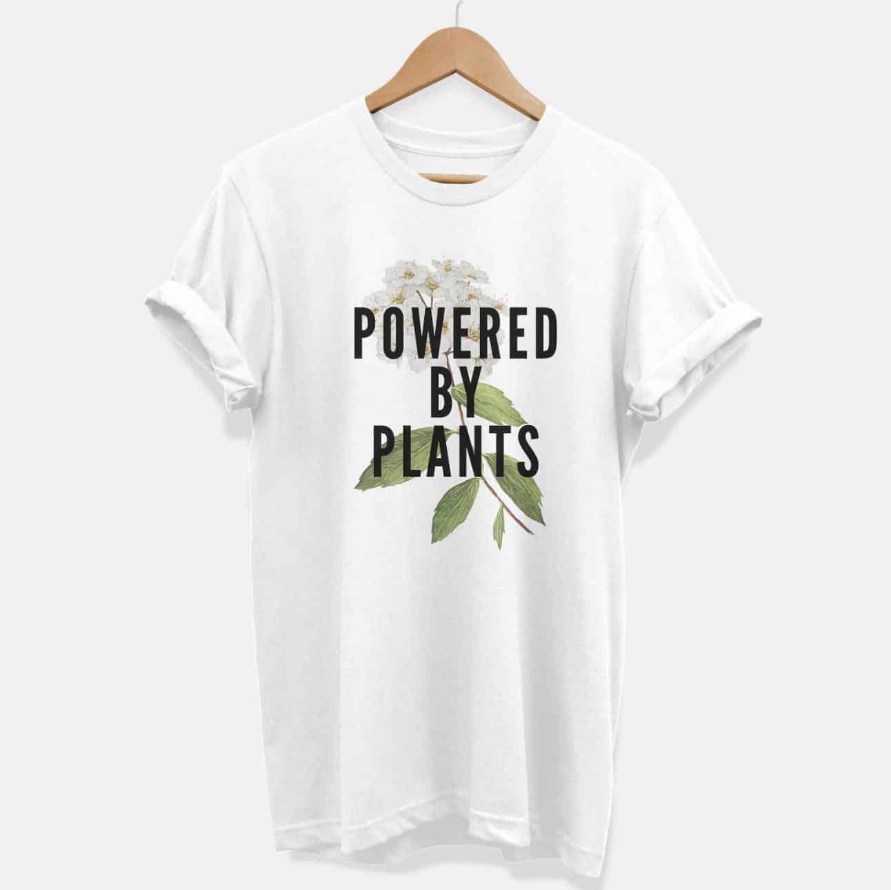 T-shirt on a hanger. T-shirt says "Powered by Plants" superimposed over a flower and stem