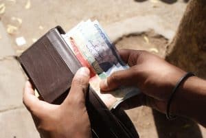 Hands shown putting cash into a wallet