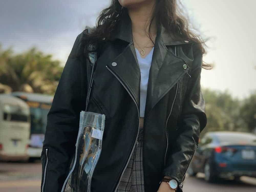Person shown wearing classic style leather jacket and carrying clear bag