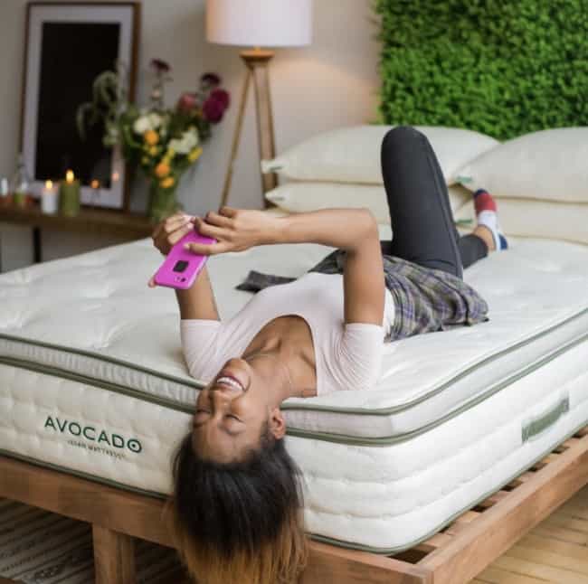 Person looking at their phone while lying on an Avocado mattress
