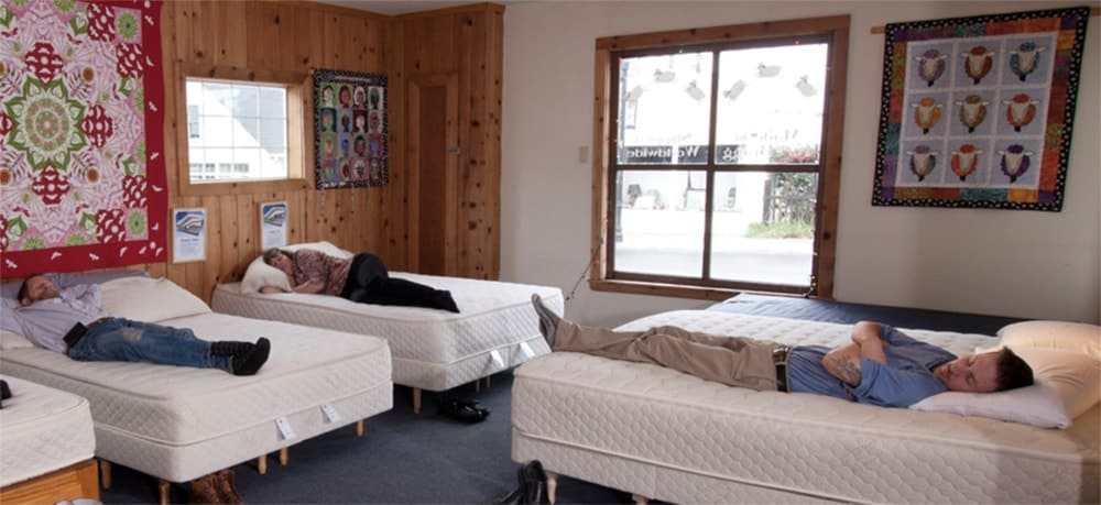 Three people lying on mattresses in FloBeds showroom