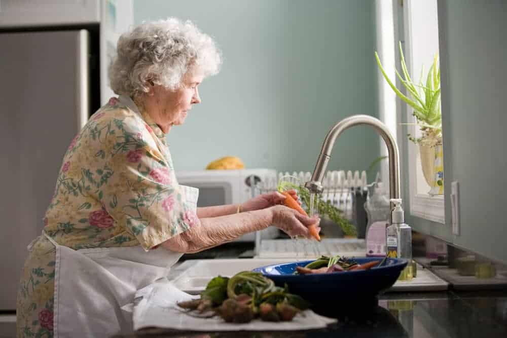 Woman shown at sink washing vegetables