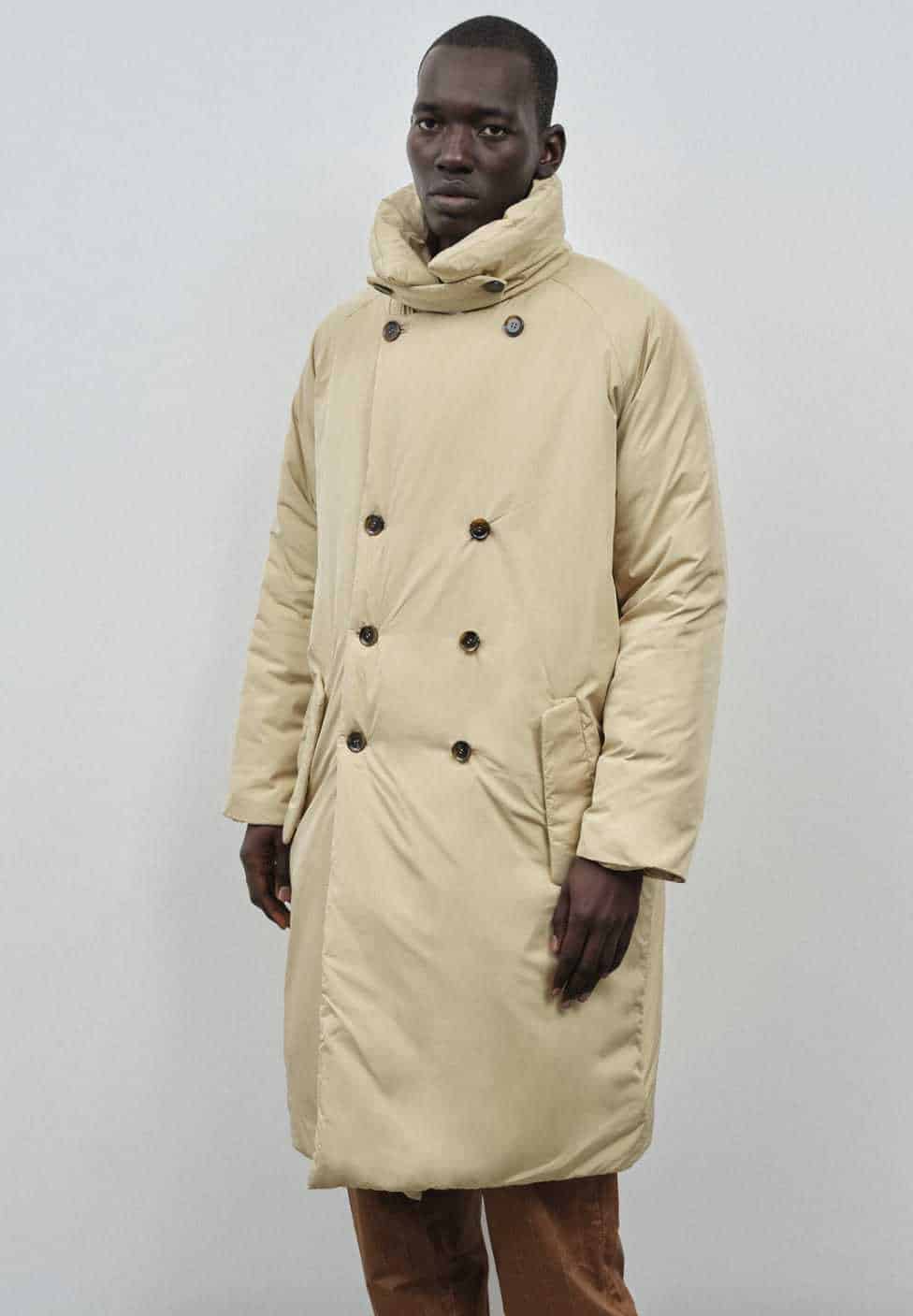 Person is shown wearing long beige puffer coat from vegan winter coats mens maker Embassy of Bricks and Logs