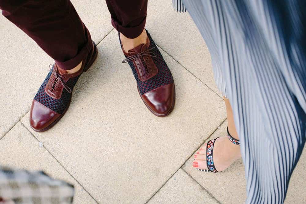 Shot of two people's dress shoes - one wearing heeled sandals, and the other brown and navy lace up oxfords