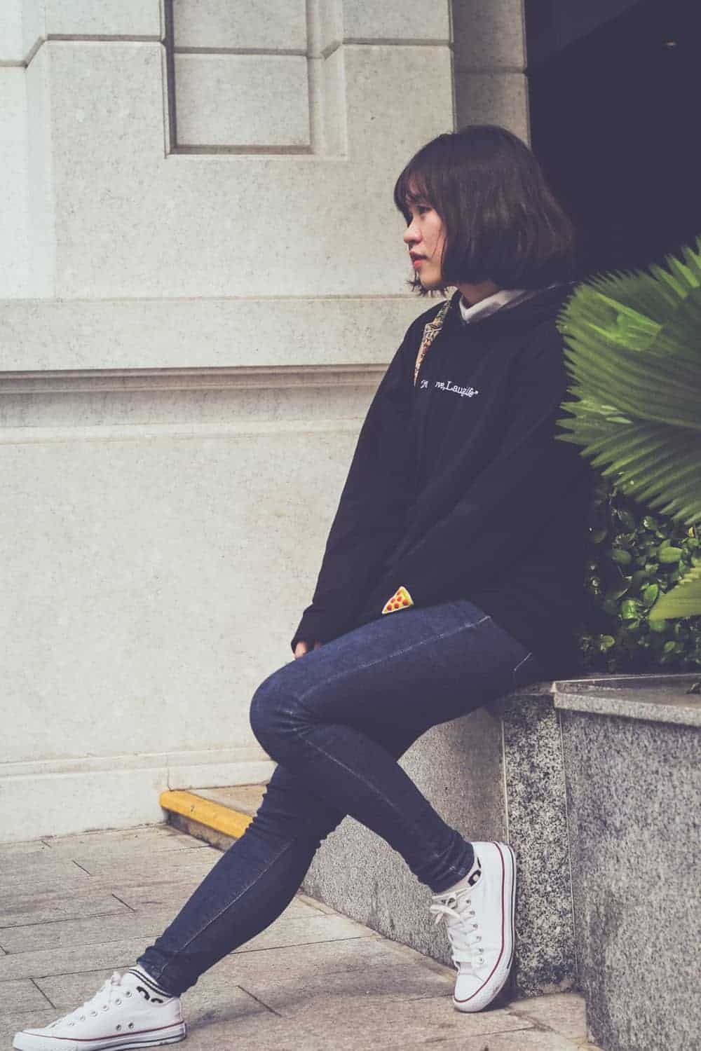 Person sitting on ledge wearing white athletic shoes