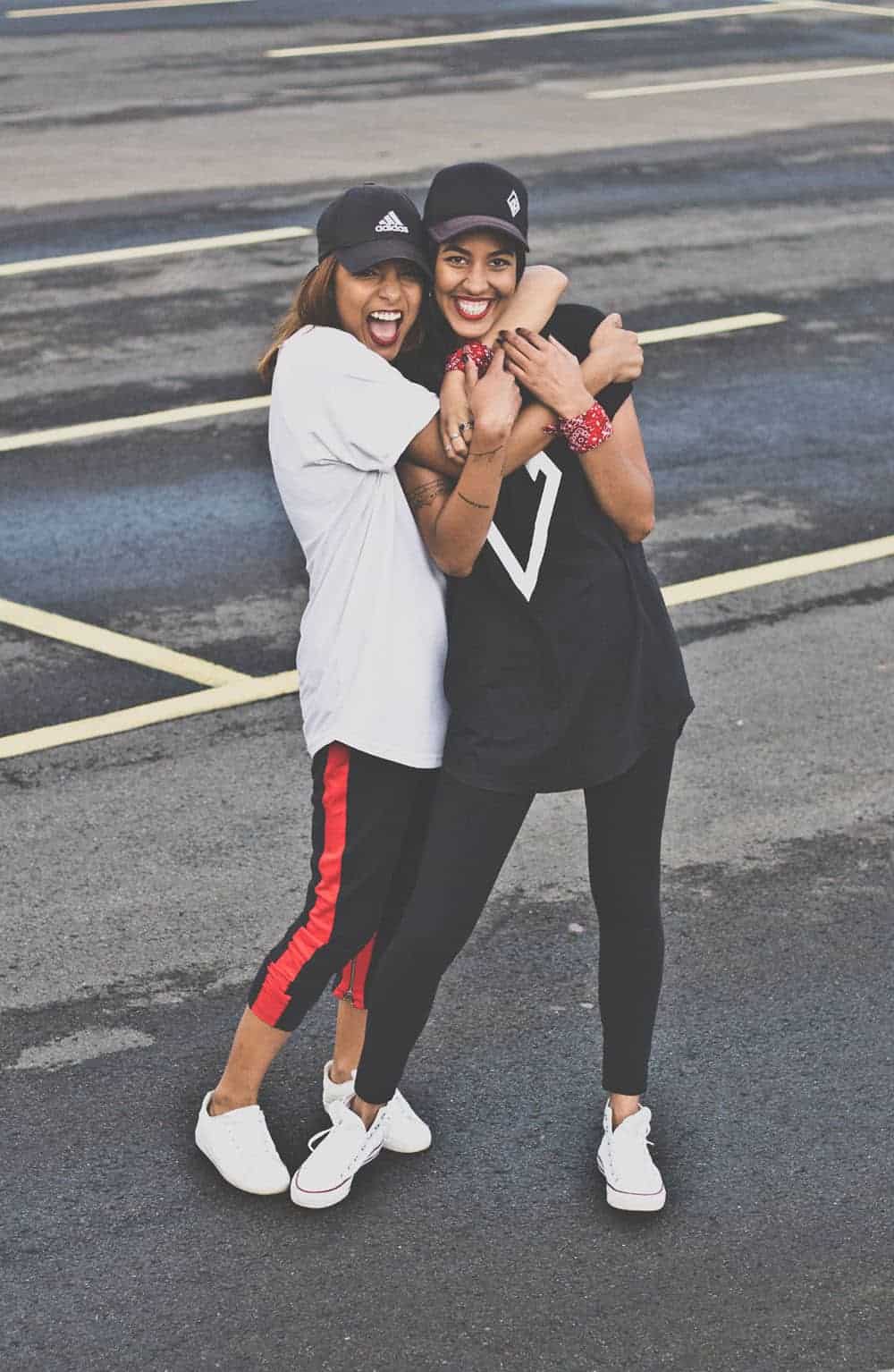 Two people hugging, wearing athletic clothes and white sneakers