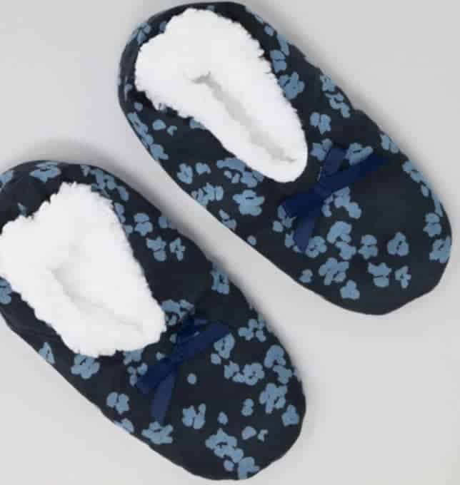 Slipper socks in a navy blue with lighter blue floral pattern and white faux wool lining visible