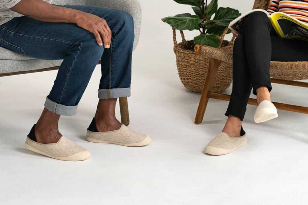 Two people are shown sitting on chairs wearing beige slippers