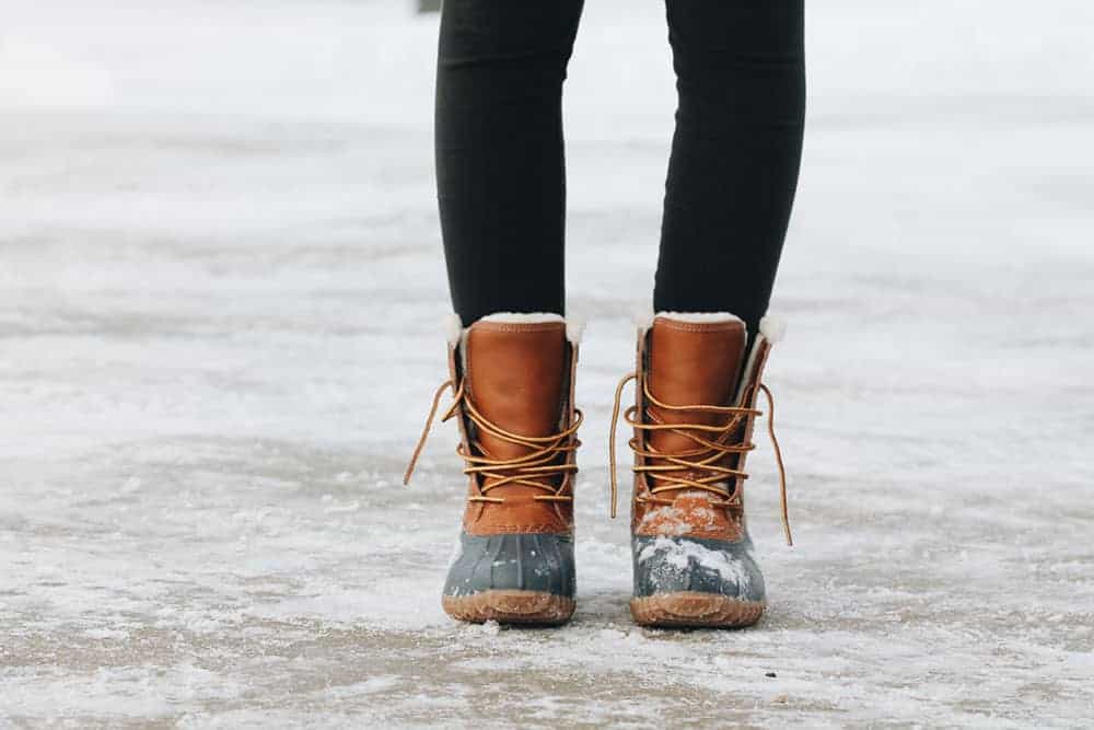 Person wearing winter boots (pictured from calves down) on icy street