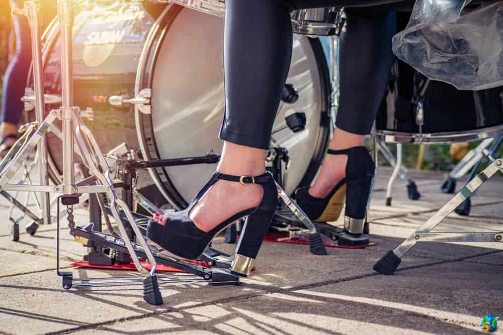 Person wearing open toed black high heels shown playing the drums