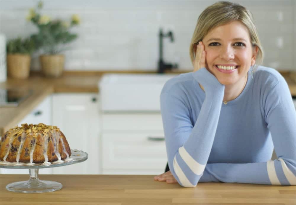 Kim from Brownble shown in kitchen next to bundt cake