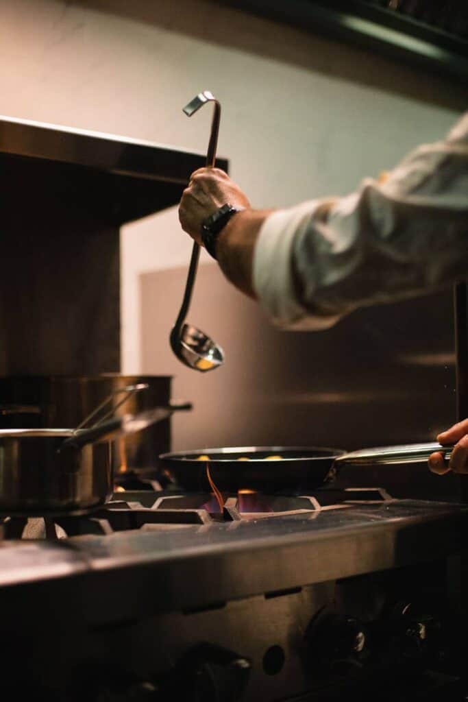 Chef ladling liquid into frying pan