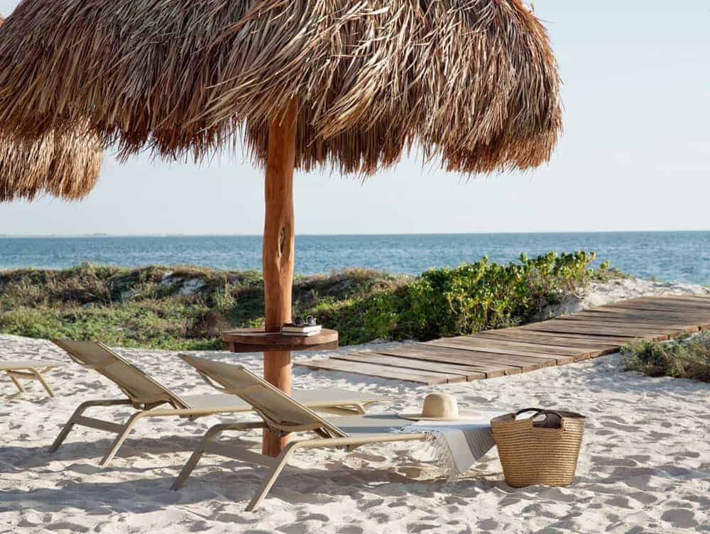 Lounge chairs underneath an umbrella on a sandy beach