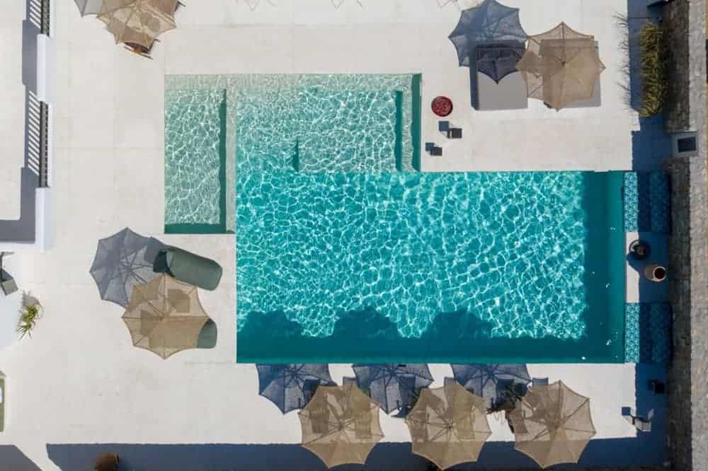 Aerial shot of pool and lounge chairs with umbrellas at Koukoumi Hotel