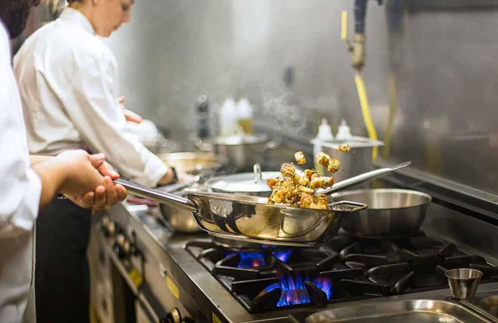 Chefs cooking food in a frying pan