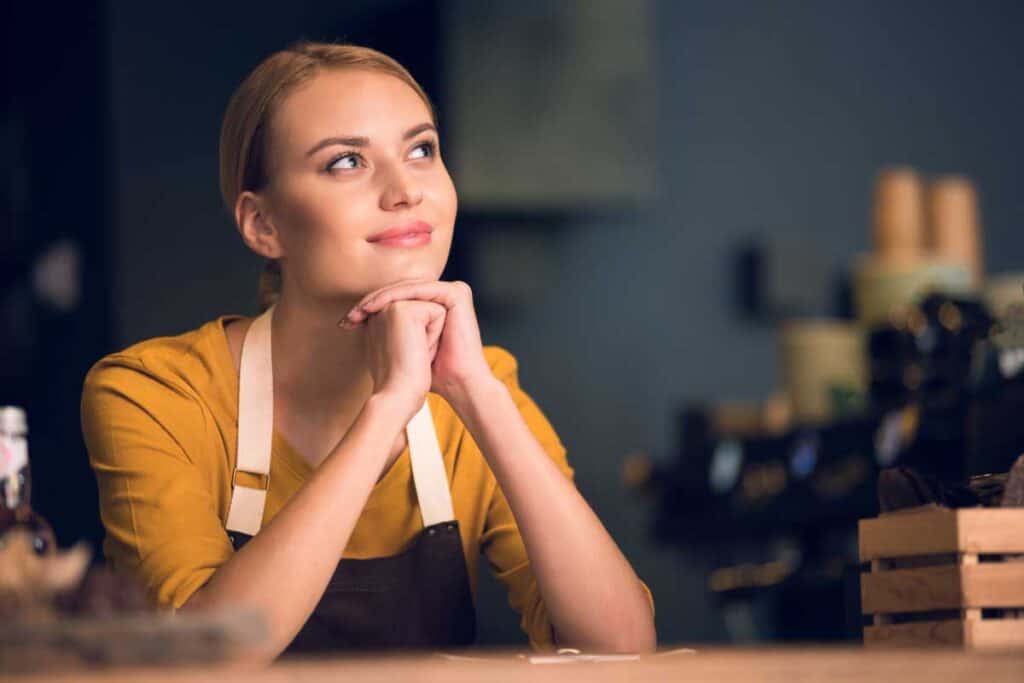 Person wearing apron sitting at table looking thoughtful