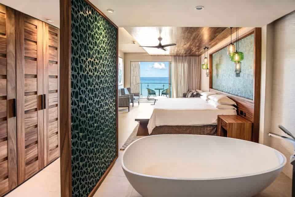 Suite with large bathtub and bed with balcony and sea views