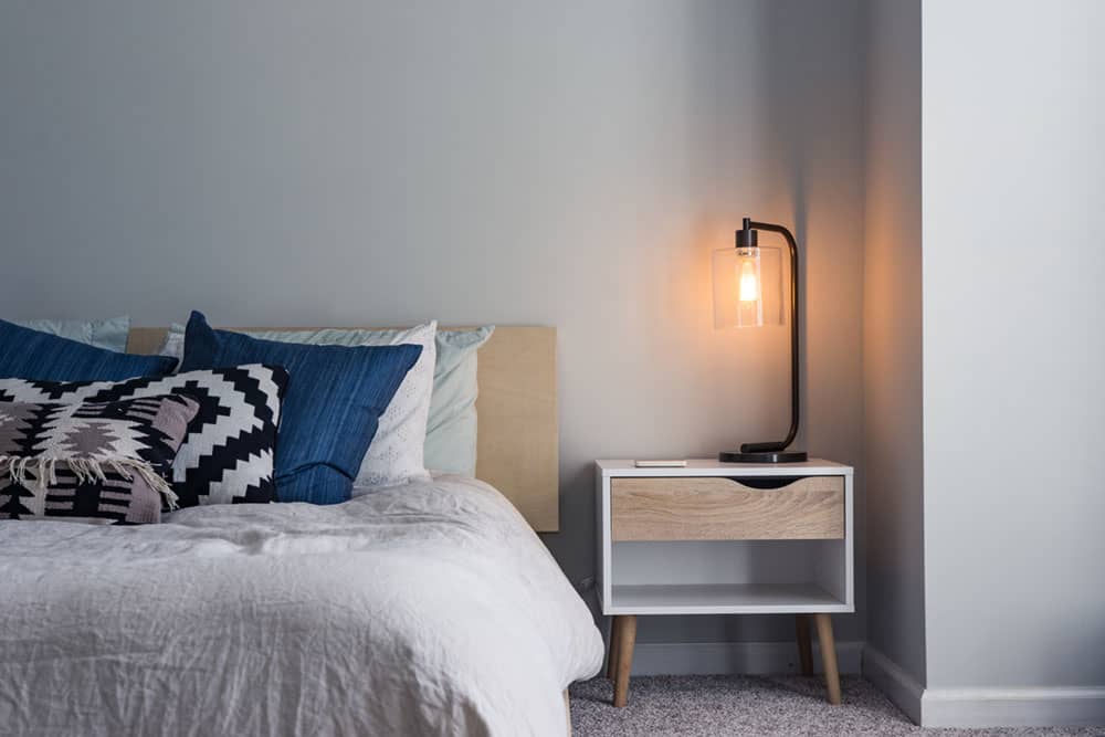 Bed with off white covers, dark blue and black and white graphic pillows