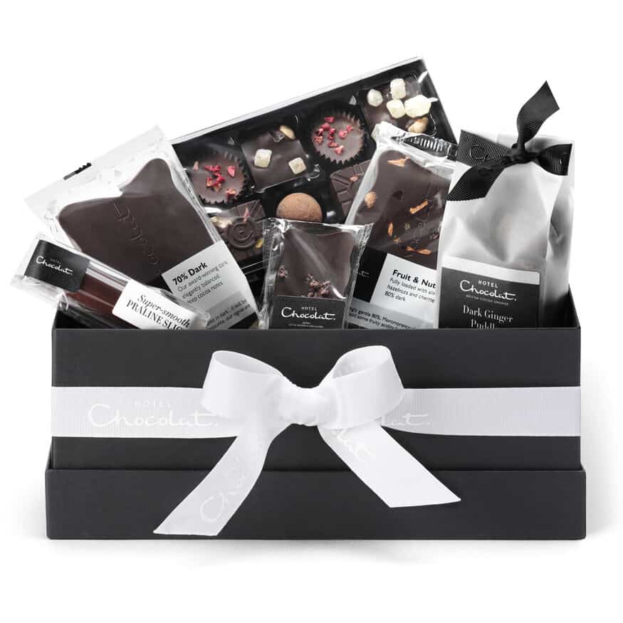 Black box with white ribbon containing variety of vegan chocolates