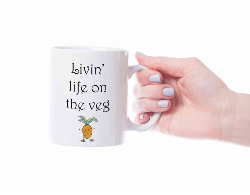 Hand holding mug that says "livin' life on the vedge" with cartoon carrot underneath