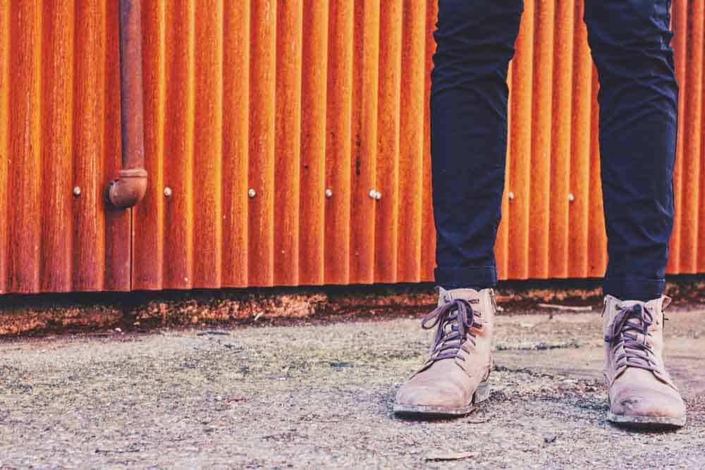 Perosn wearing jeans and boots in front of orange wall