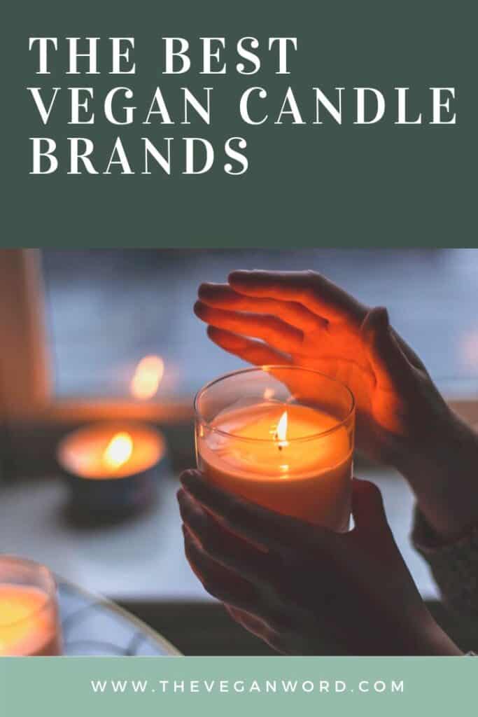 Pinterest image showing hand holding burning candle with more candles in the background. Text reads "the best vegan candle brands"