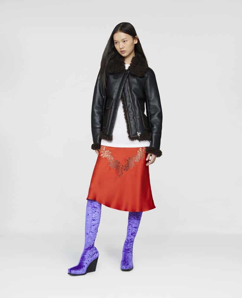 Model wearing vegan black leather and faux further bomber jacket, white shirt, red slip skirt and purple boots from Stella McCartney